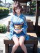 A woman in a blue kimono sitting on a wooden bench.