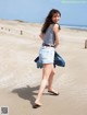 A woman walking on a sandy beach with her back to the camera.