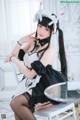 A woman in a maid outfit sitting on a chair.