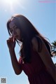 A woman in a red dress standing in front of a blue sky.