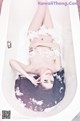 A woman laying in a bathtub with feathers on her body.