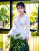 A woman in a white dress holding a bunch of bamboo.