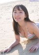 A woman in a bikini laying on the sand.