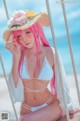 A woman with pink hair wearing a white bikini and a straw hat.