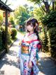 A woman in a kimono standing in the middle of a street.