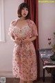 a woman in a pink dress standing next to a table