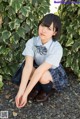 A young woman in a school uniform sitting on the ground.