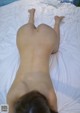 A naked woman laying on a bed with her back to the camera.