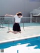 A woman jumping into a swimming pool with her arms outstretched.