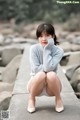 A woman sitting on a stone wall with her legs crossed.