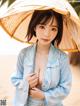 A woman in a blue robe holding an umbrella on the beach.