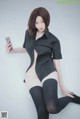 A woman in a black shirt and stockings holding a cell phone.