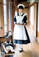 A woman in a maid outfit holding a tray of food.