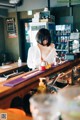 A woman standing behind a bar in a restaurant.