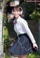 A young woman in a school uniform with headphones on.