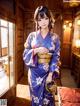 A woman in a blue kimono standing in a room.