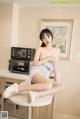 A woman sitting on top of a white table in a kitchen.