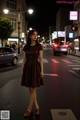 A woman standing in the middle of a city street at night.